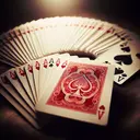 Create an image of an ordinary deck of cards spread out in a fan-like shape. Towards the front of the image, focus on a single card flipped showing its face. The card is the Ace of Hearts, vibrant red in color and intricately patterned. To emphasize, show some of the other cards partially turned over, revealing their identities as black suits - Spades and Clubs. The setting is on a smooth velvet table cloth, under a mellow, golden lighting. No text should appear in the image.